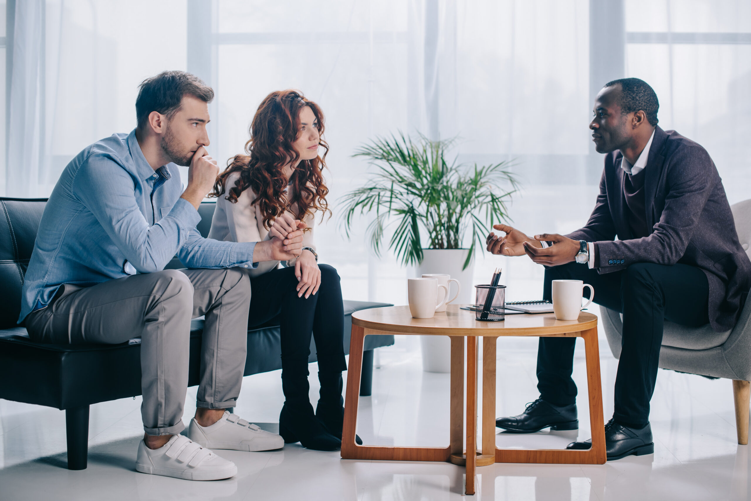 Smiling african american psychiatrist talking to young couple in office