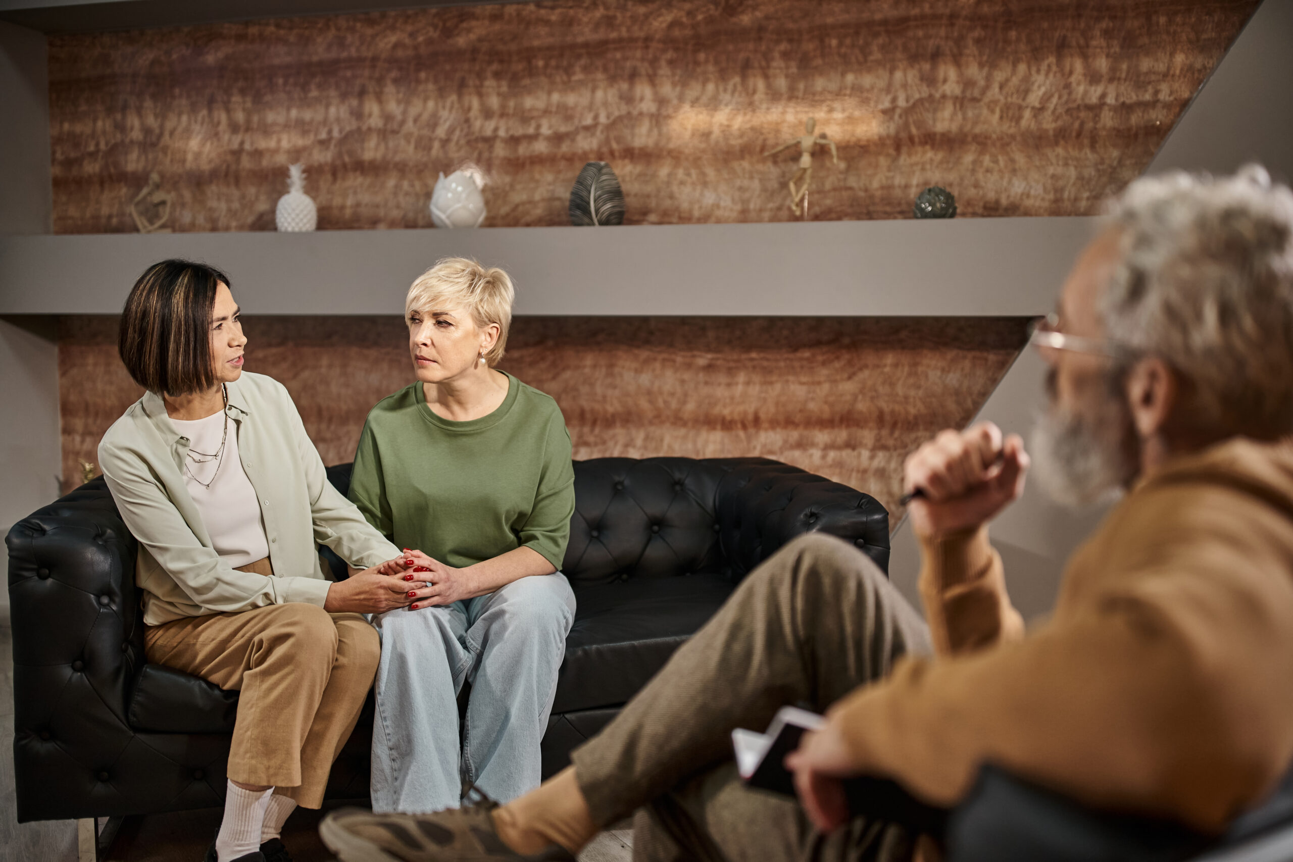 middle aged psychologist in glasses listening to worried lesbian couple talking during session